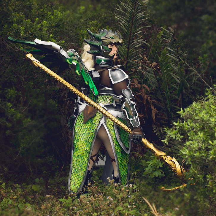 Woman in green scay armor and gold staff