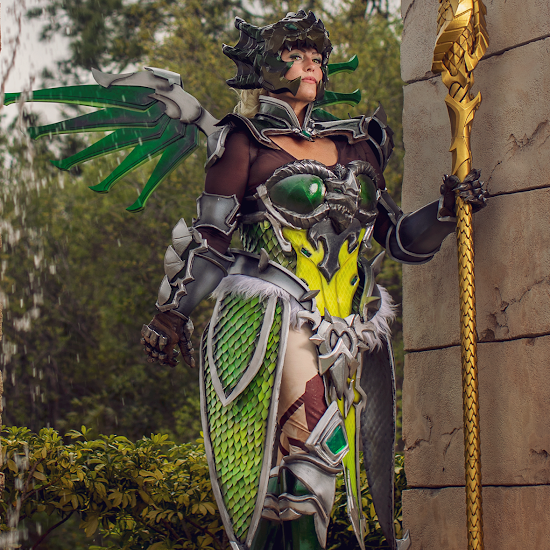 Woman in green scay armor and gold staff