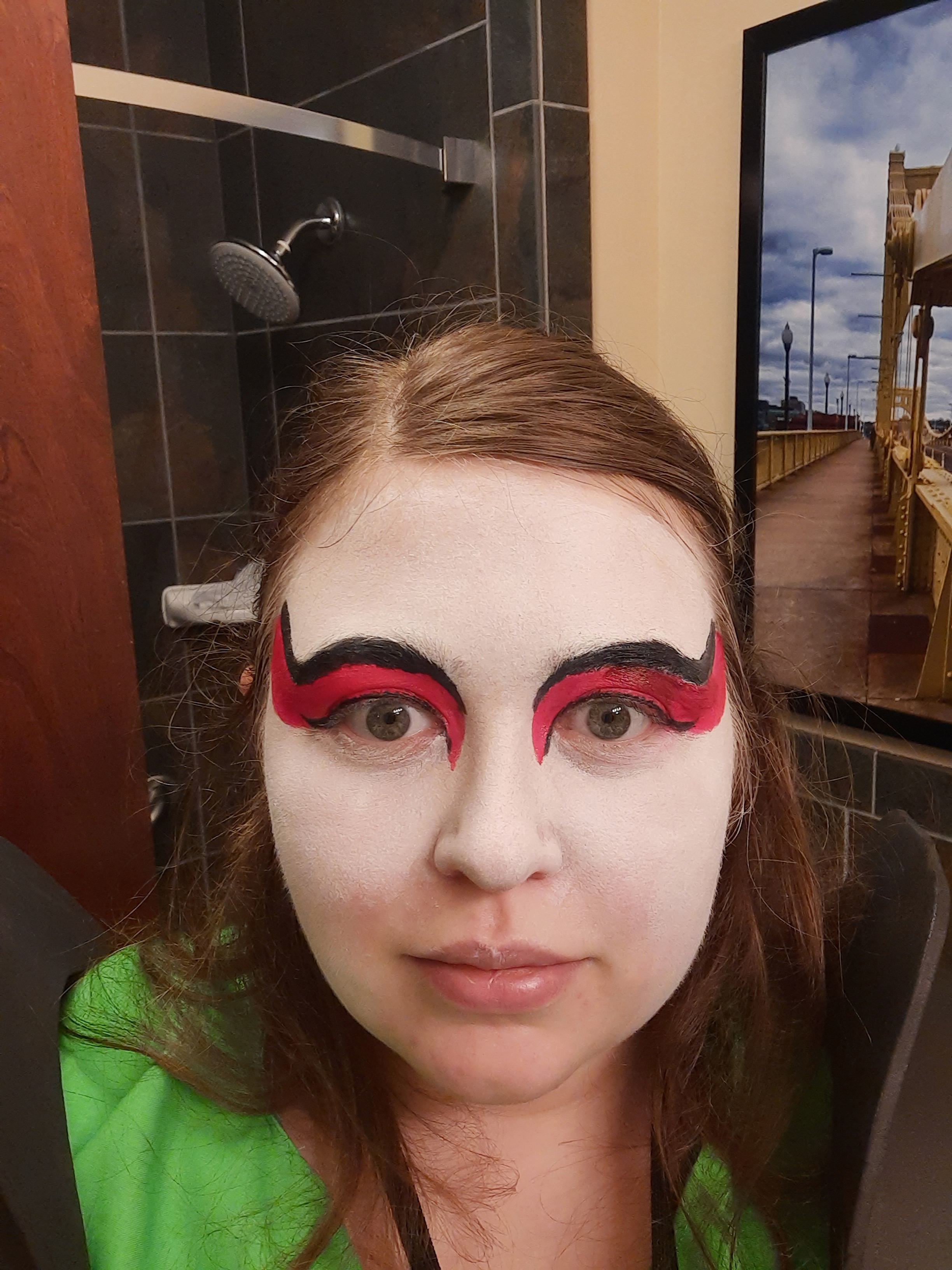 Three female cosplayers. They are dressed in dark green skirt with diagonal pleats, light green long jackets with long poofy sleeves, and leather (plether) armor and wrist guards. They have white face paint with red eye makeup. Due to covid had to wear white masks with red lips to stay safe but keep the look. They are holding large wooden fans.