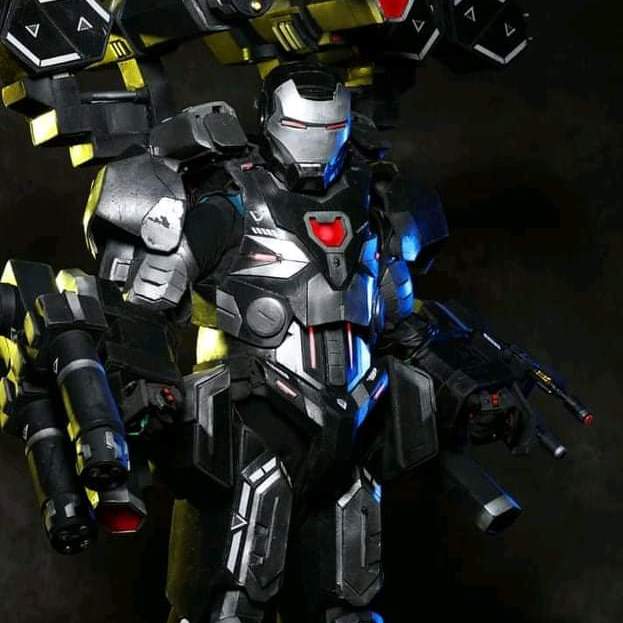 War Machine, in grey armor, stands seriously and at the ready.