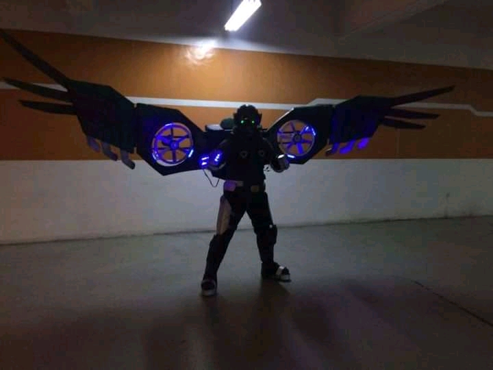 Armored suit in silhouette. The suit has spread wings and lit-up circular fans in the wings.